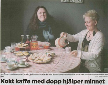 Foto av tidningsartikel, Två kvinnor fikar vid runt bord